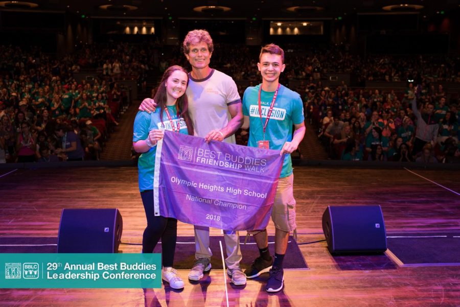 Olympic Heights Best Buddies Club officers Courtney Reiff (left) and Jacob Pasternack (right) accept a banner recognizing the OH chapter as the top fundraiser in the nation from Anthony Kennedy Shriver, Best Buddies International founder.