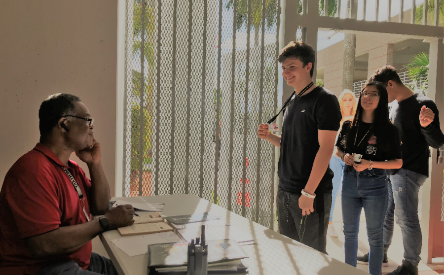 School security monitor Mr. Robert Police (seated) checks student ID badges of (from front to back) Hunter Moneck, Katelynn Dos Santos, Jose Simbaco, and Jenny Paul as they enter through the new security gate at the front entrance to the Olympic Heights campus.