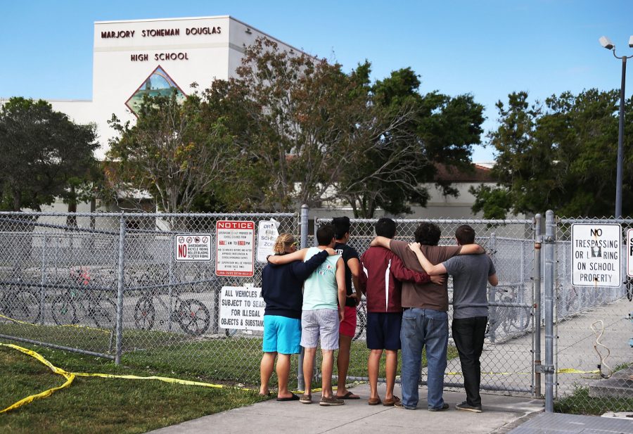 PARKLAND, FL - FEBRUARY 18:  People look on at the Marjory Stoneman Douglas High School on February 18, 2018 in Parkland, Florida. Police arrested 19 year old former student Nikolas Cruz for the mass shooting that killed 17 people on February 14.  (Photo by Joe Raedle/Getty Images)