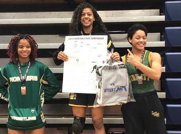 Olympic Heights wrestler Leidaly Rivera (center) on the medalist platform after winning her second consecutive state championship.