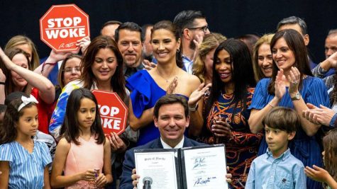Florida governor Ron DeSantis, with school children as backdrop props, displays the Florida bill known as the Stop WOKE Act he signed into law on April 22. The law went into effect on July 1.